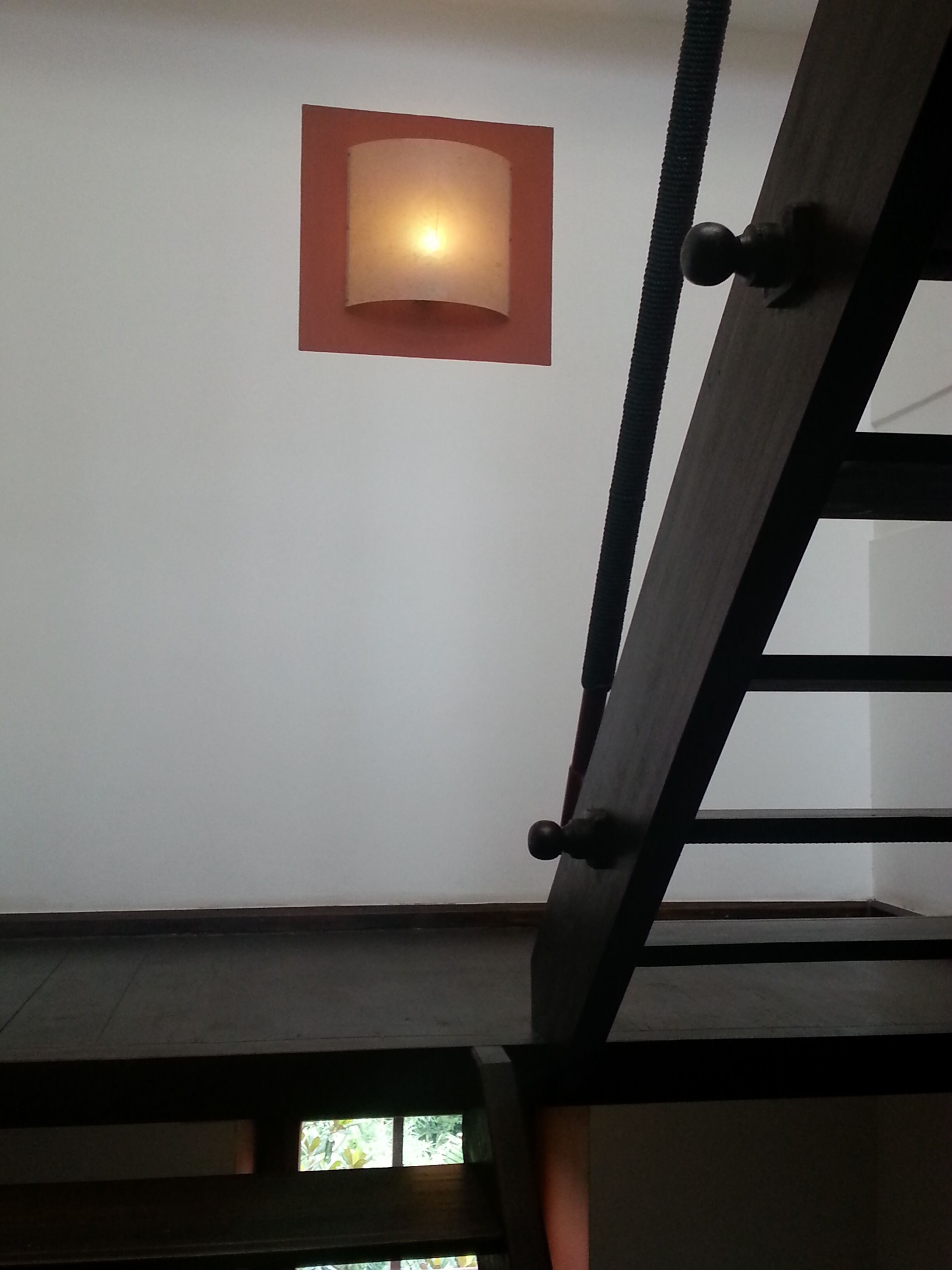 A staircase with a wooden handrail and a wall-mounted light fixture.
