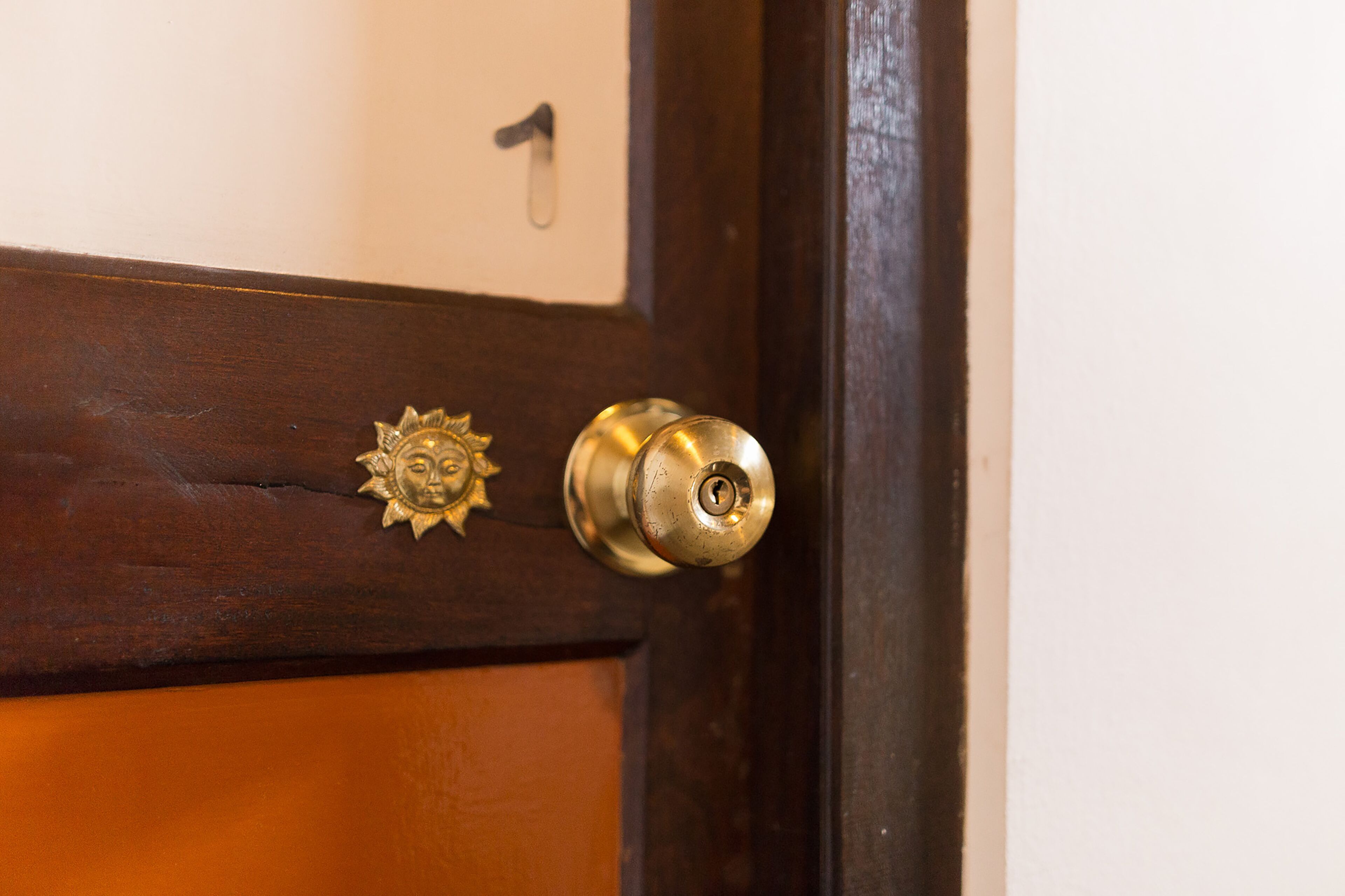 A door with a brass doorknob and a sun-shaped handle.