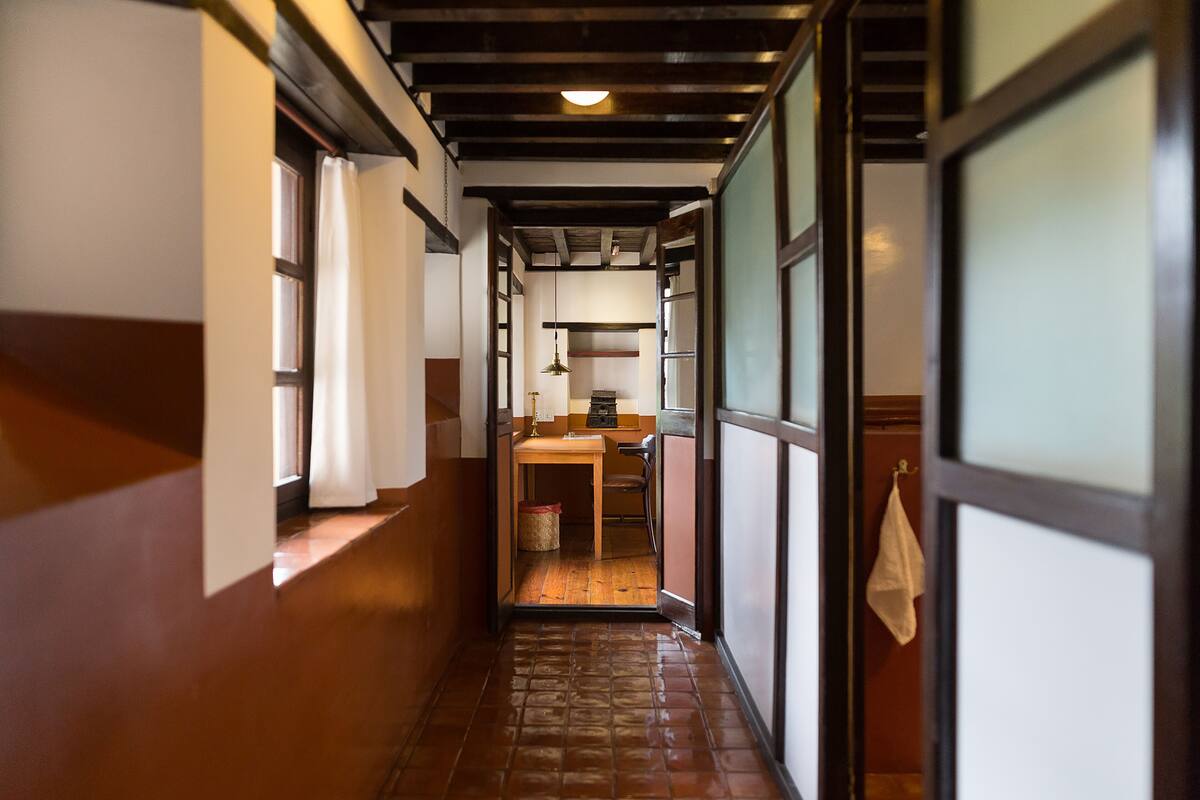 Un couloir étroit, doté d’un plancher en bois, et une cuisine visible au fond.