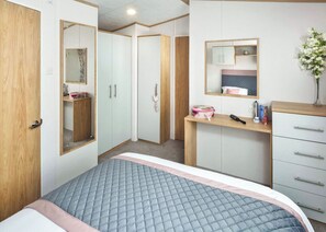 A bedroom with a bed, a wardrobe, a mirror, and a dresser. - 2 bedroom accommodation in Axminster (Axminster)