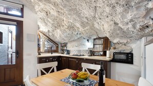 Une cuisine avec un plafond rustique, des armoires en bois, une table à manger avec des fruits et du pain, et un four à micro-ondes.
