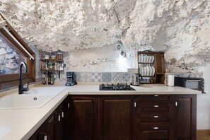 A kitchen with a stone ceiling, wooden cabinets, a built-in stove, and a microwave.