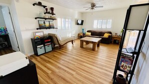 Un salon spacieux doté d’un parquet, d’un canapé marron, d’une table basse en bois et d’un ventilateur de plafond.