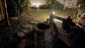 Un jardin agrémenté d’un foyer extérieur, de rochers et de différentes plantes.