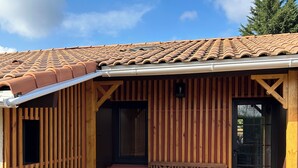 Una cabaña de madera con techo de tejas, una banca y una jardinera con plantas.