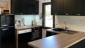 Una cocina moderna con armarios oscuros, un refrigerador negro y una encimera de madera.