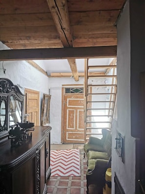 A rustic room with exposed wooden beams, a wooden door, a sofa, and a table with decorative items.