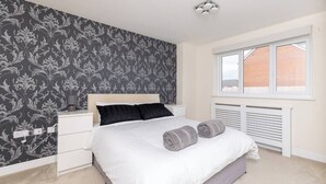 Une chambre à coucher avec un lit, des tables de chevet, une fenêtre et un radiateur.