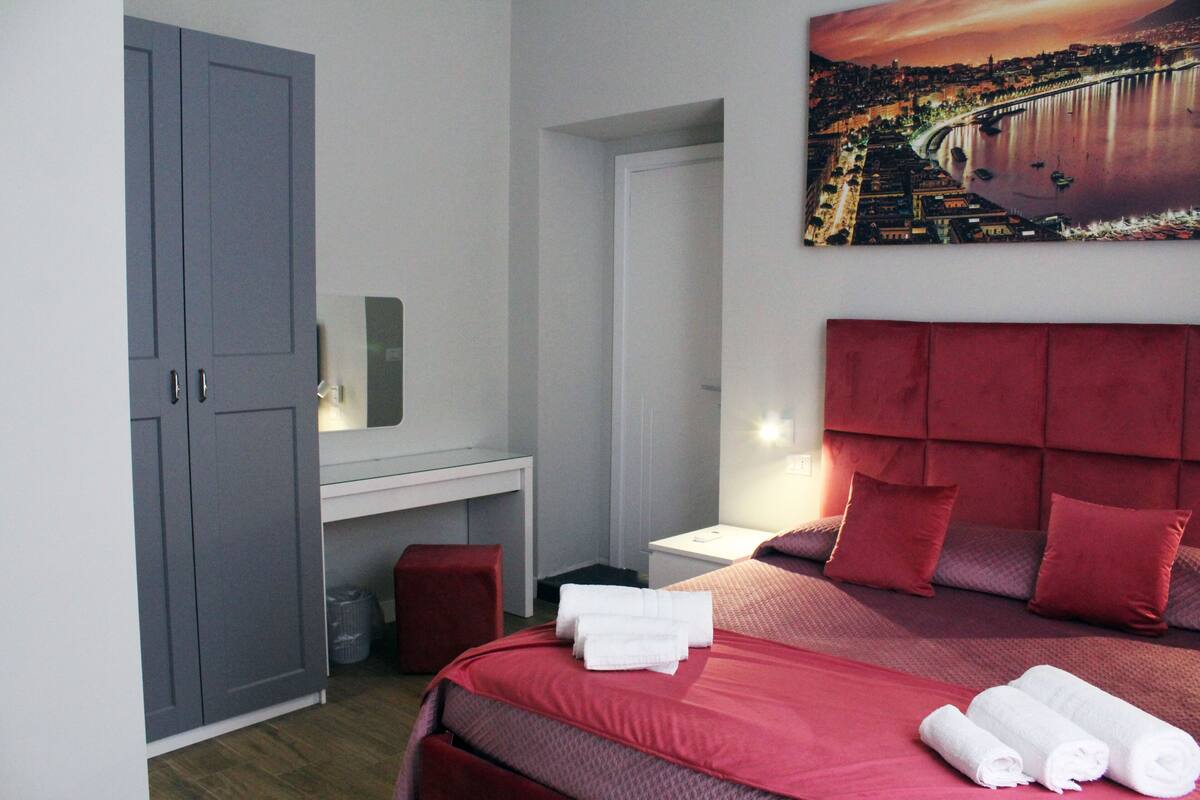 Quarto de hotel com uma cama grande, uma escrivaninha e um guarda-roupa.