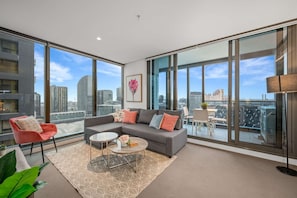 A modern living room with a grey sofa, a small round coffee table, and a red chair.