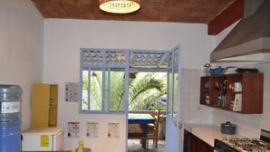 Une cuisine équipée d’une cuisinière à gaz, d’un distributeur d’eau et d’un coin repas avec une table et des chaises.