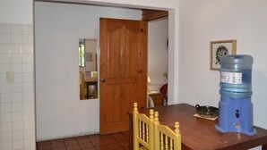 Une cuisine avec une porte en bois, un distributeur d’eau et une table à manger avec des chaises.
