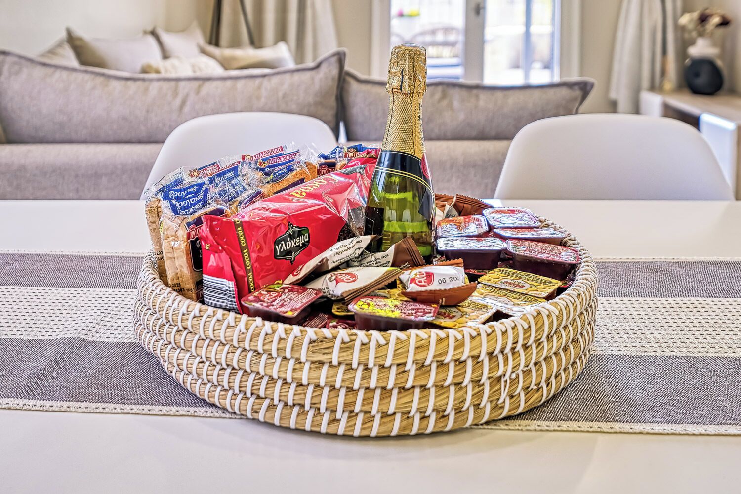 Une table à manger avec un panier en osier contenant divers aliments et une bouteille de champagne.