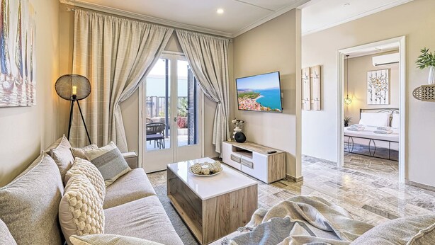 A modern living room with a sofa, coffee table, TV, and a balcony view. - Katerina's Place (ARGOS)