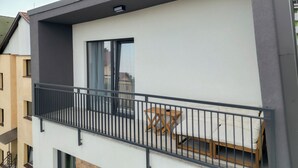 A modern apartment with a balcony, a sliding glass door, and a small wooden table. - ZEN Garden Apartments (Cluj-Napoca)