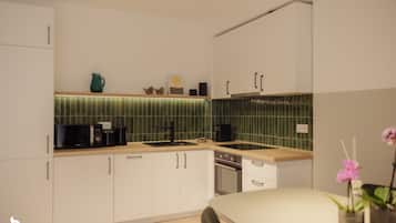 Una cocina moderna con armarios blancos, salpicadero verde y encimera de madera.