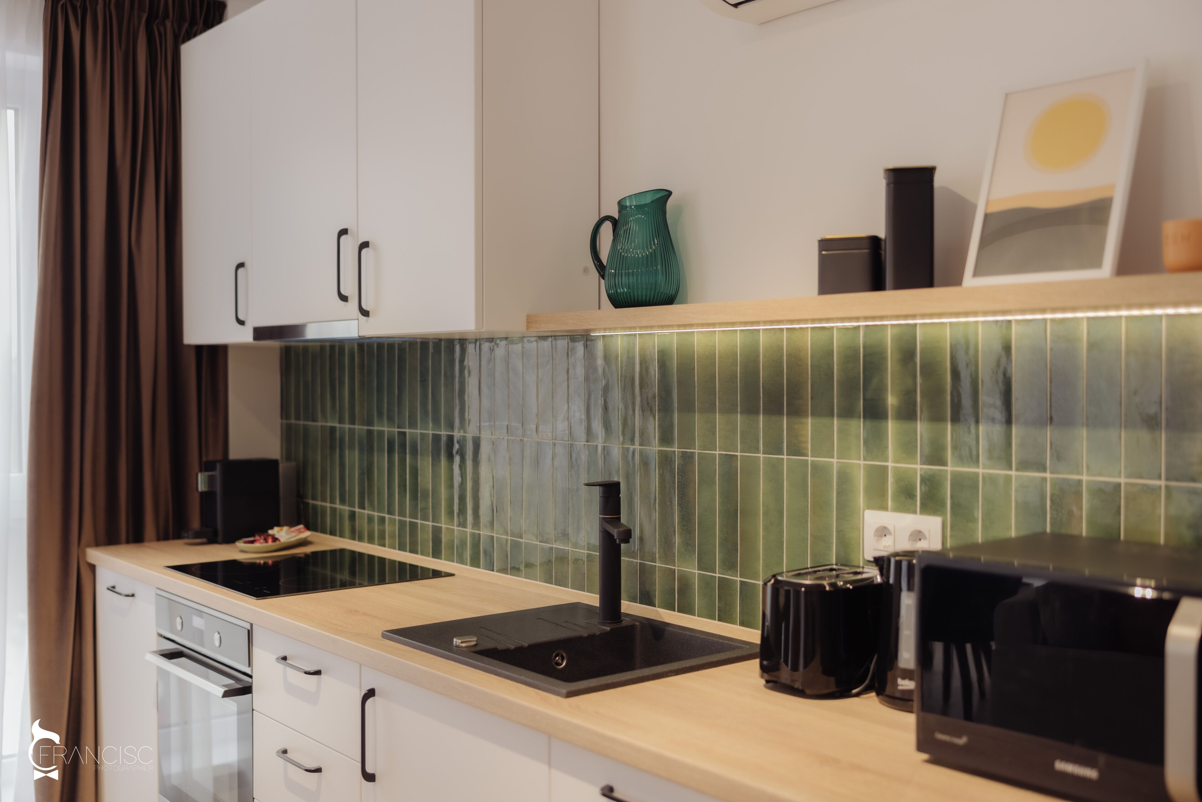A modern kitchen with a built-in oven, a sink, a coffee maker, and a microwave.