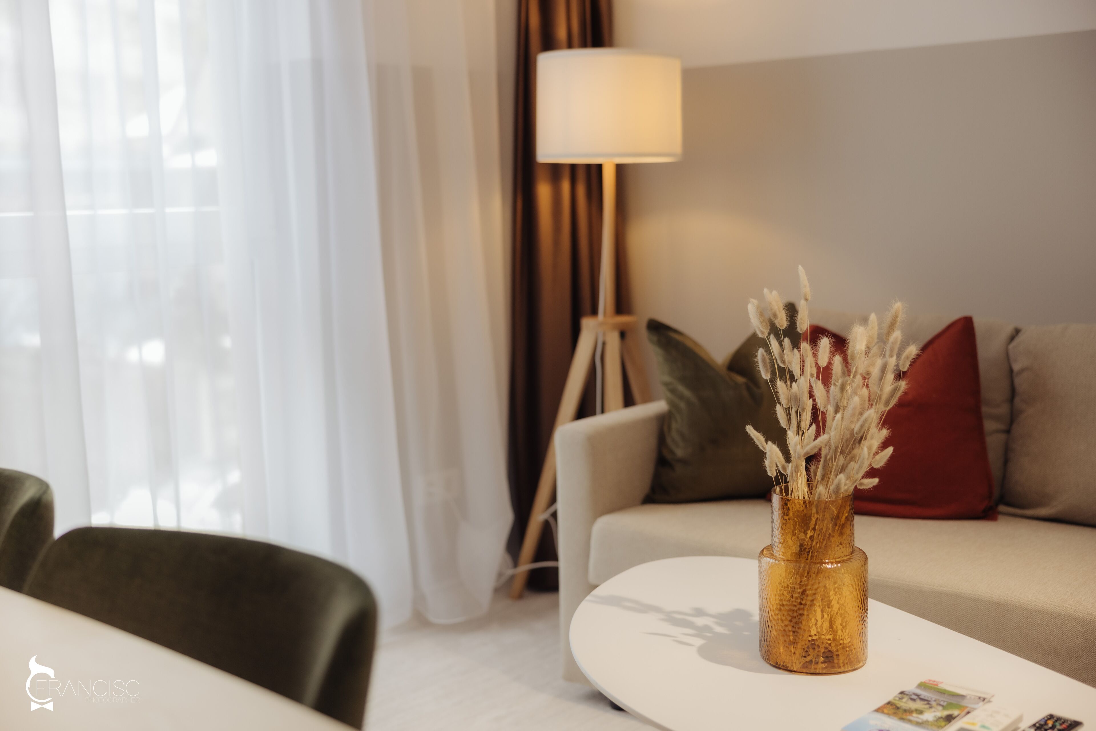Ein modernes Wohnzimmer mit einem weißen Sofa, einem runden Couchtisch und einer Vase mit Trockenpflanzen.