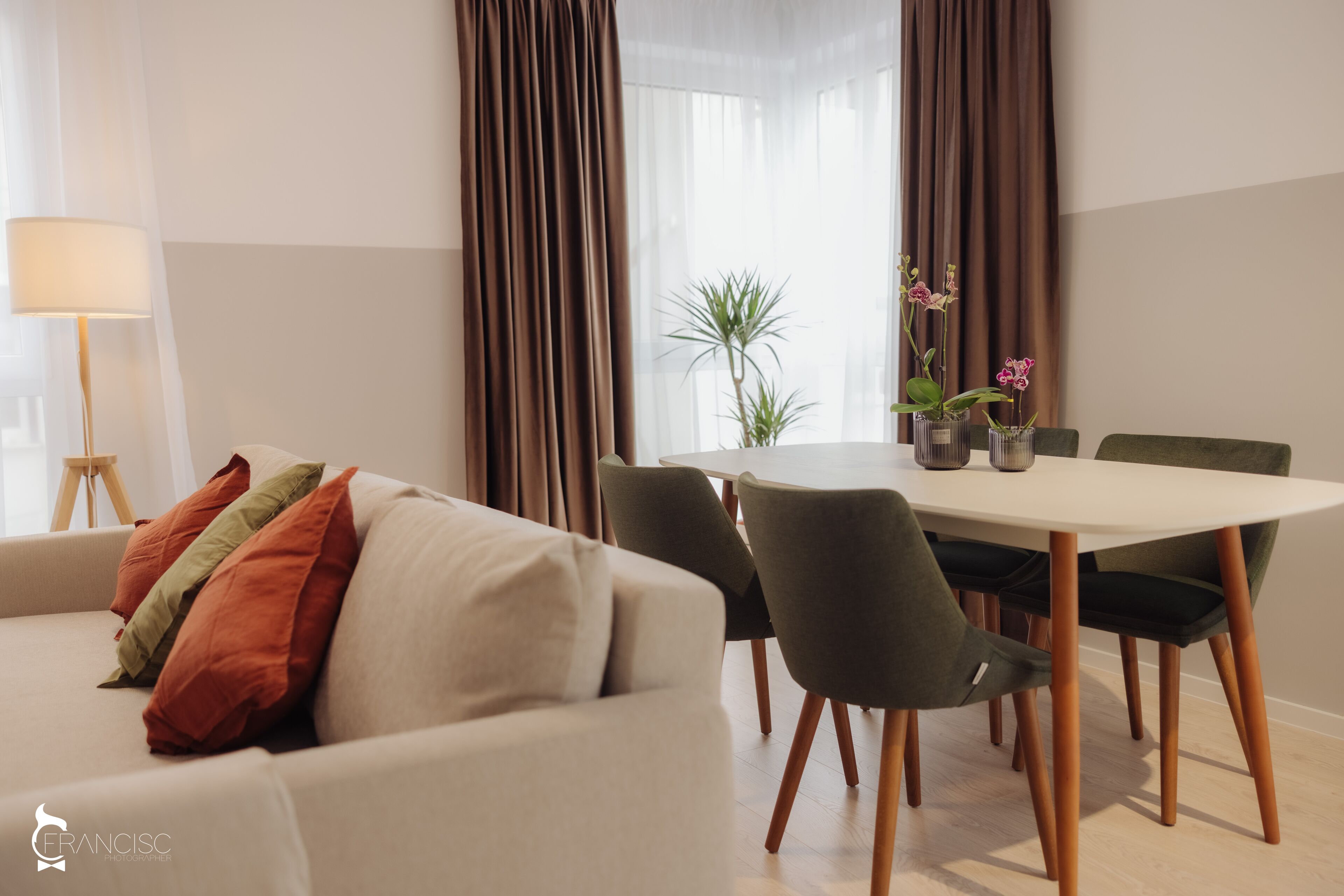 A modern living room with a sofa, dining table, chairs, and a lamp.