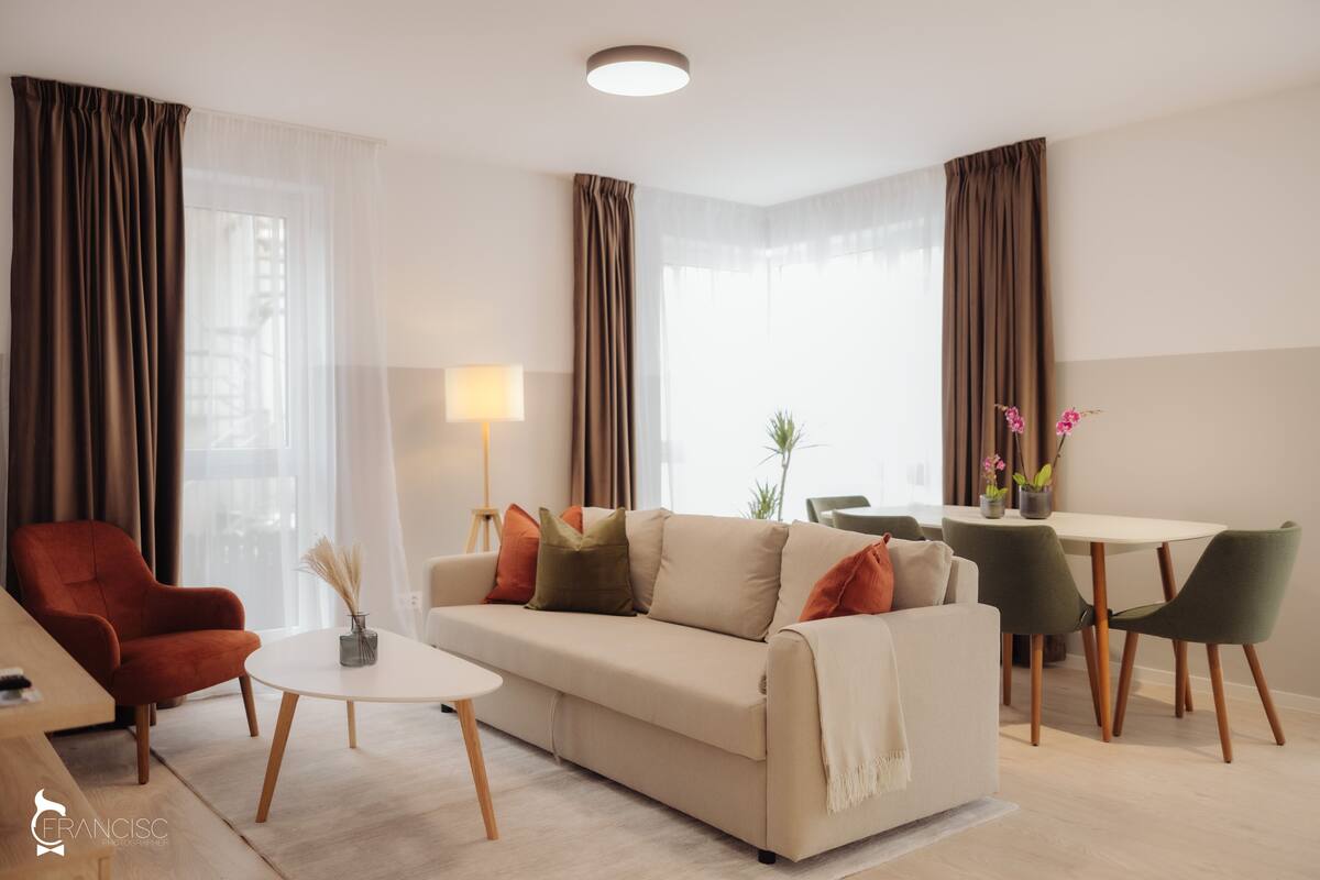 Ein modernes Wohnzimmer mit Sofa, Sessel, Couchtisch und Essbereich.