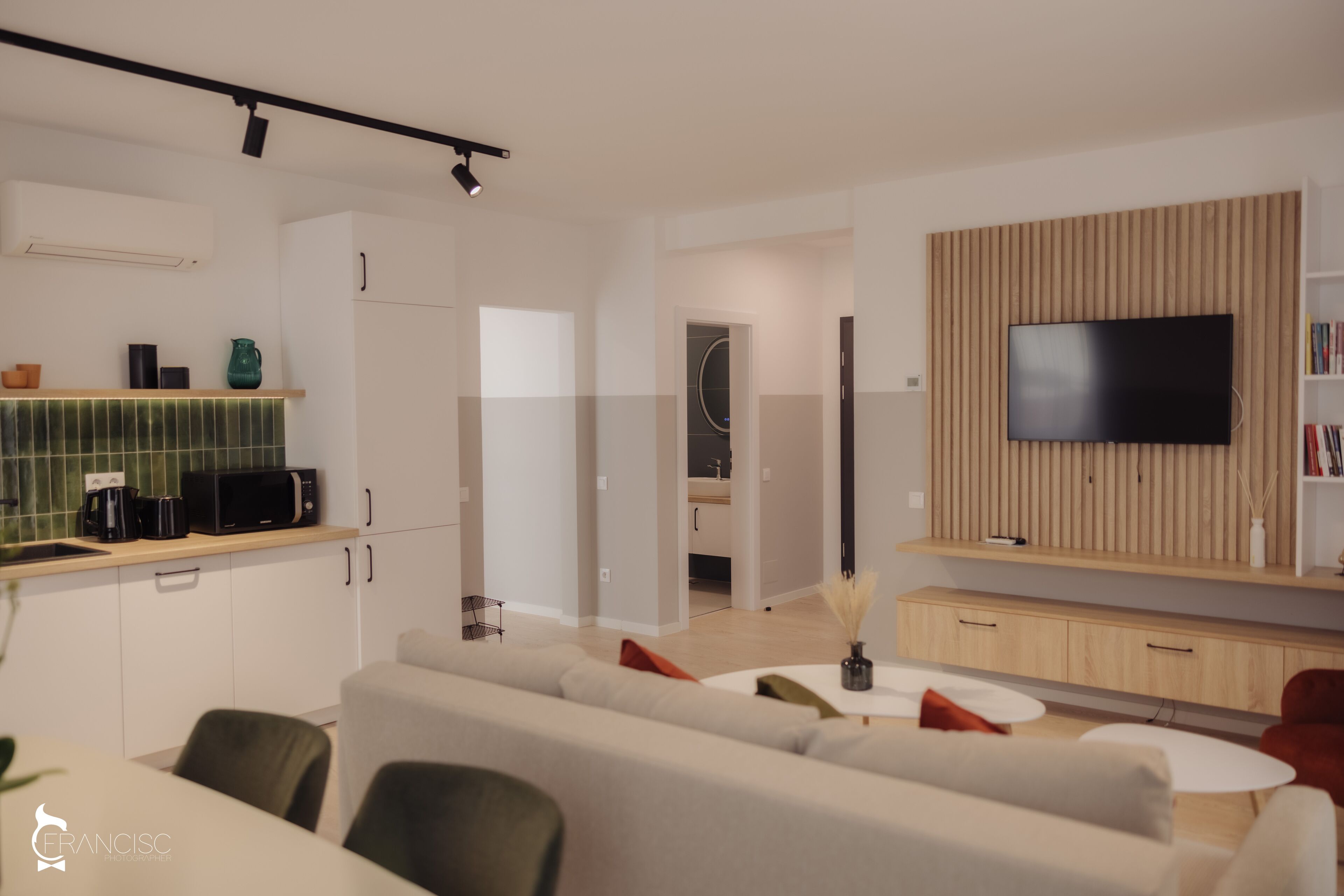 Un salon moderne doté d’un grand téléviseur à écran plat, d’un canapé et d’un coin repas avec une table et des chaises.