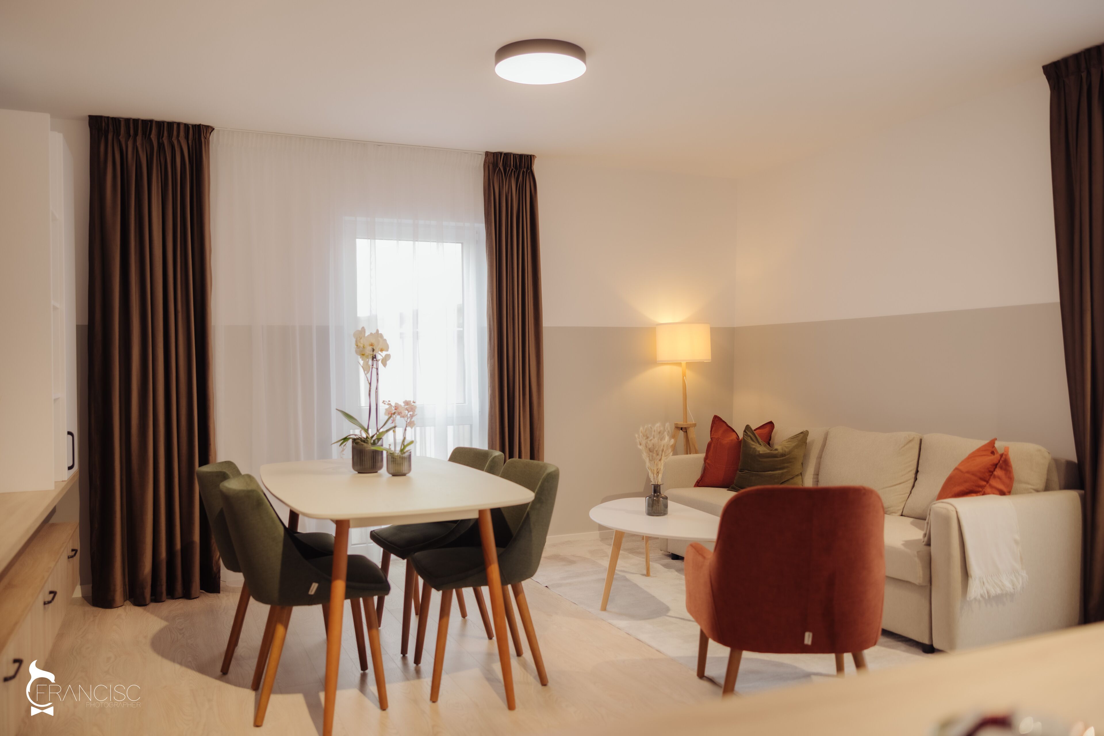 A modern living room with a dining table, chairs, a sofa, and a lamp.