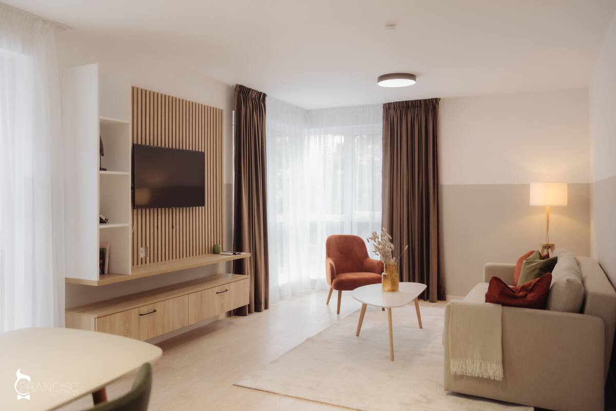 Ein modernes Wohnzimmer mit Flachbildfernseher, einer Couch, einem Couchtisch und einem Essbereich.