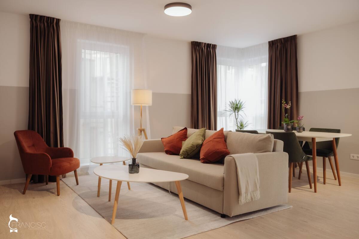 Ein modernes Wohnzimmer mit Sofa, Sesseln, Couchtisch und Essbereich.
