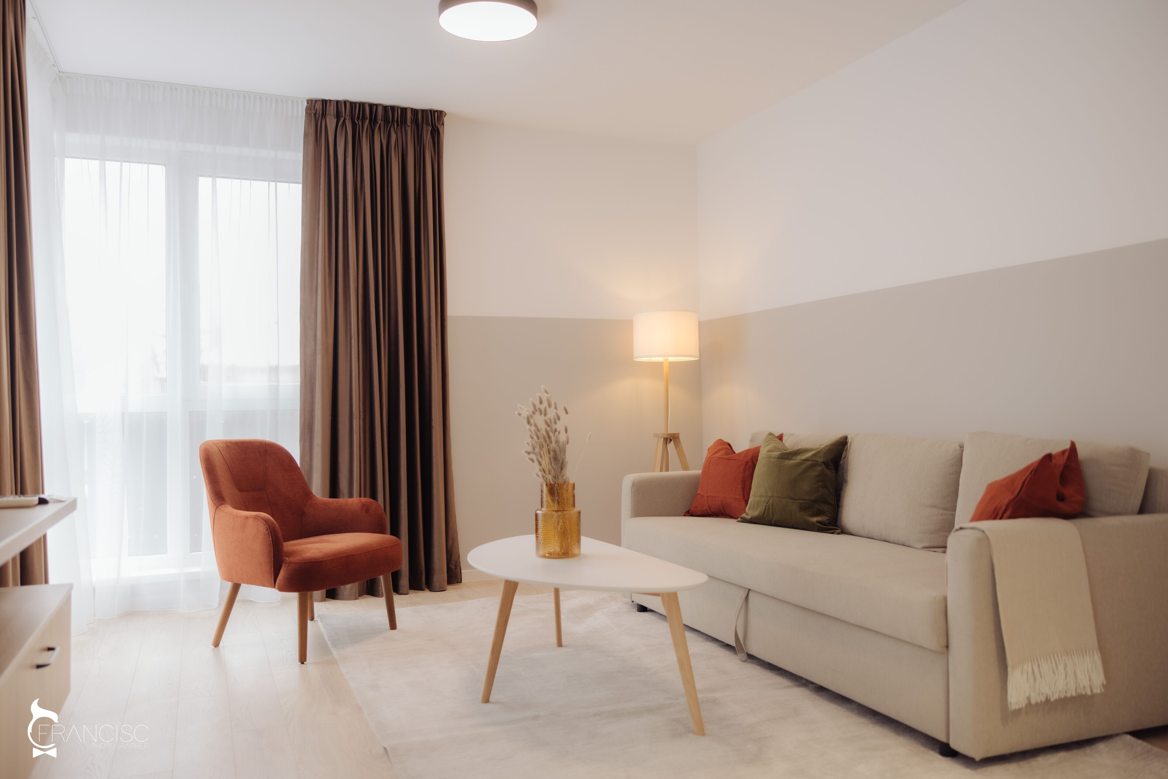 A modern living room with a sofa, armchair, and a small table with a vase.