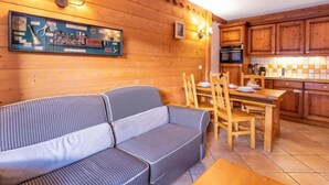 Ein gemütliches Zimmer mit einer Couch, einem Esstisch und Holzschränken.