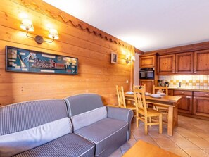 Een gezellige kamer met een bank, eettafel en houten kasten.