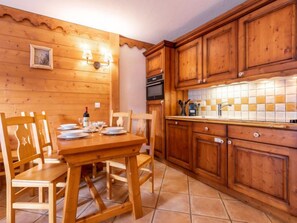 Een houten interieur met een eettafel gedekt voor vier personen, houten kasten en een betegelde spatwand.