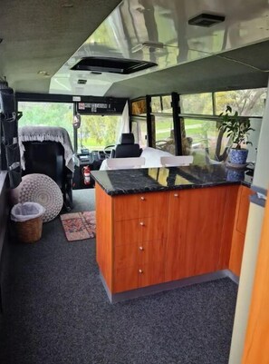 Compact kitchen area with a sink, stove, and wooden countertop, perfect for preparing meals on the go.