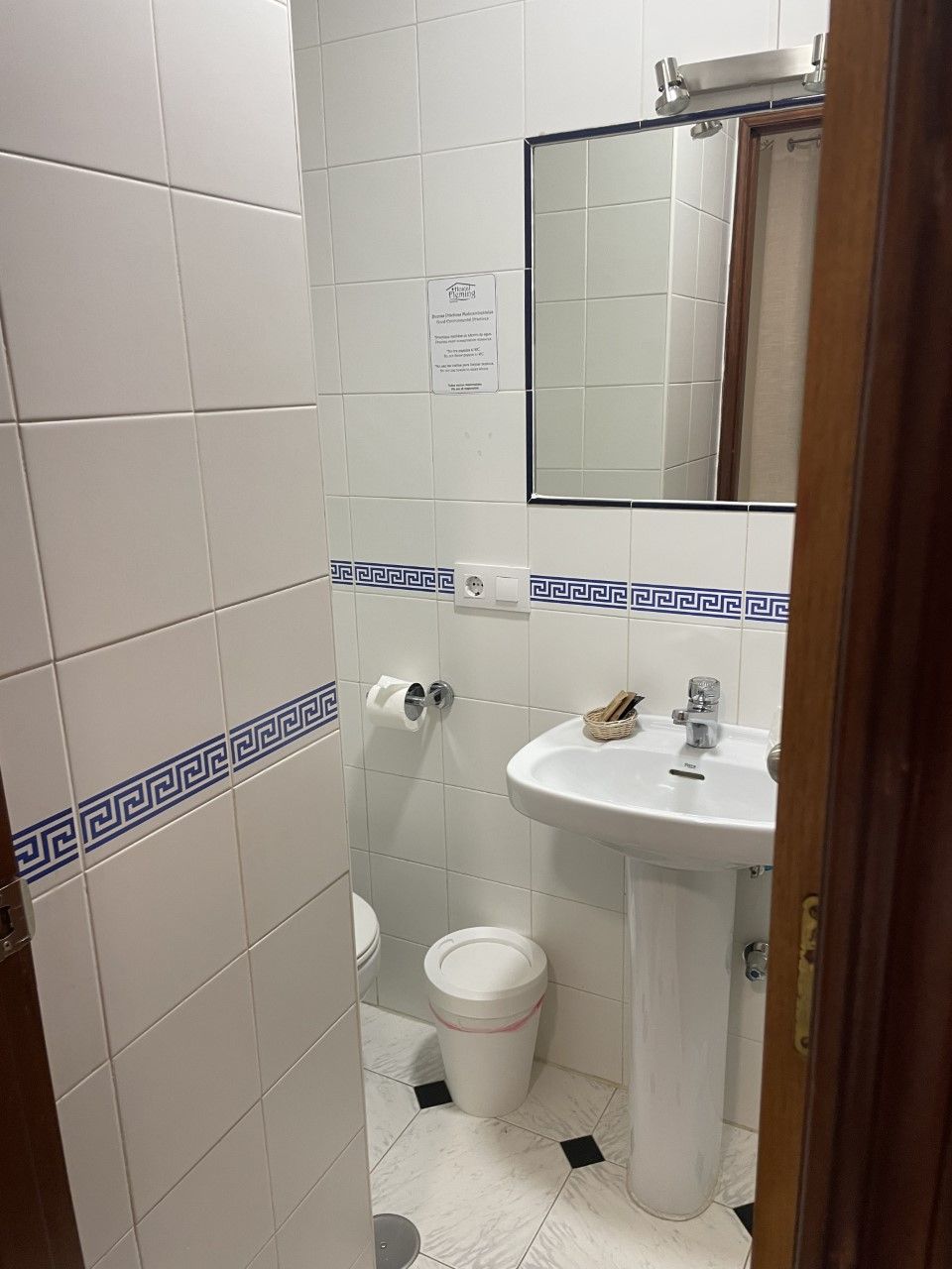 A bathroom with a white sink, a mirror, and a toilet.