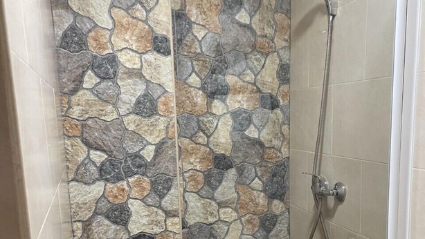 Un área de ducha con pared de piedra y ducha.