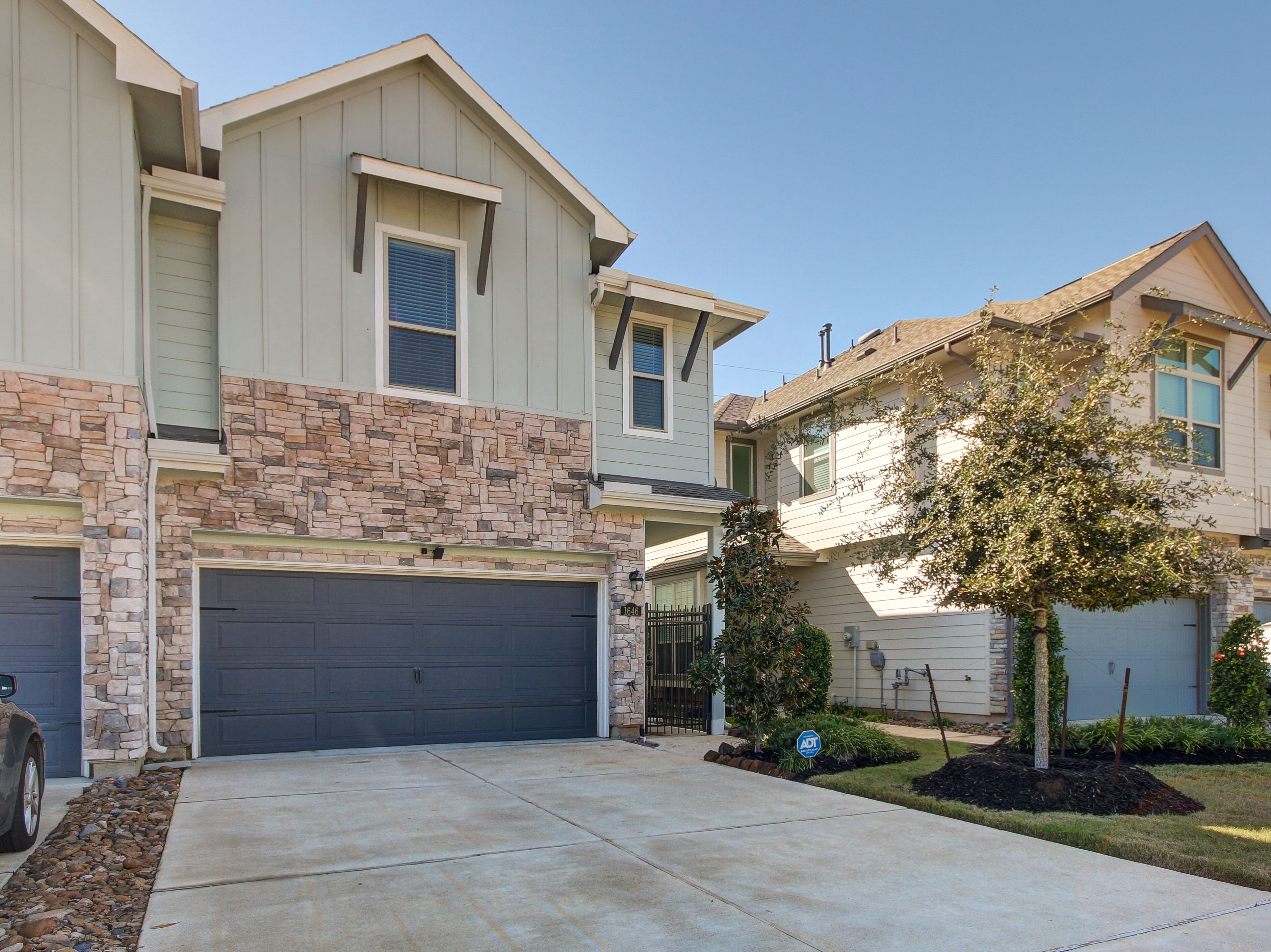 A two-story house with a stone facade, a garage, and a well-maintained lawn.