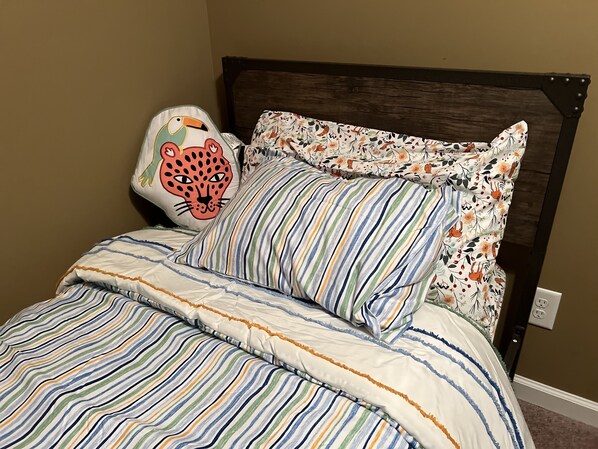 A bed with striped bedding and a leopard pillow.