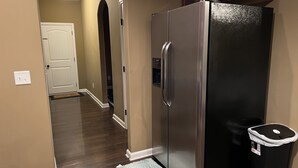 A kitchen with a stainless steel refrigerator, a trash can, and a wooden floor. - Five Stars Luxury Clean Home (Clarksville)