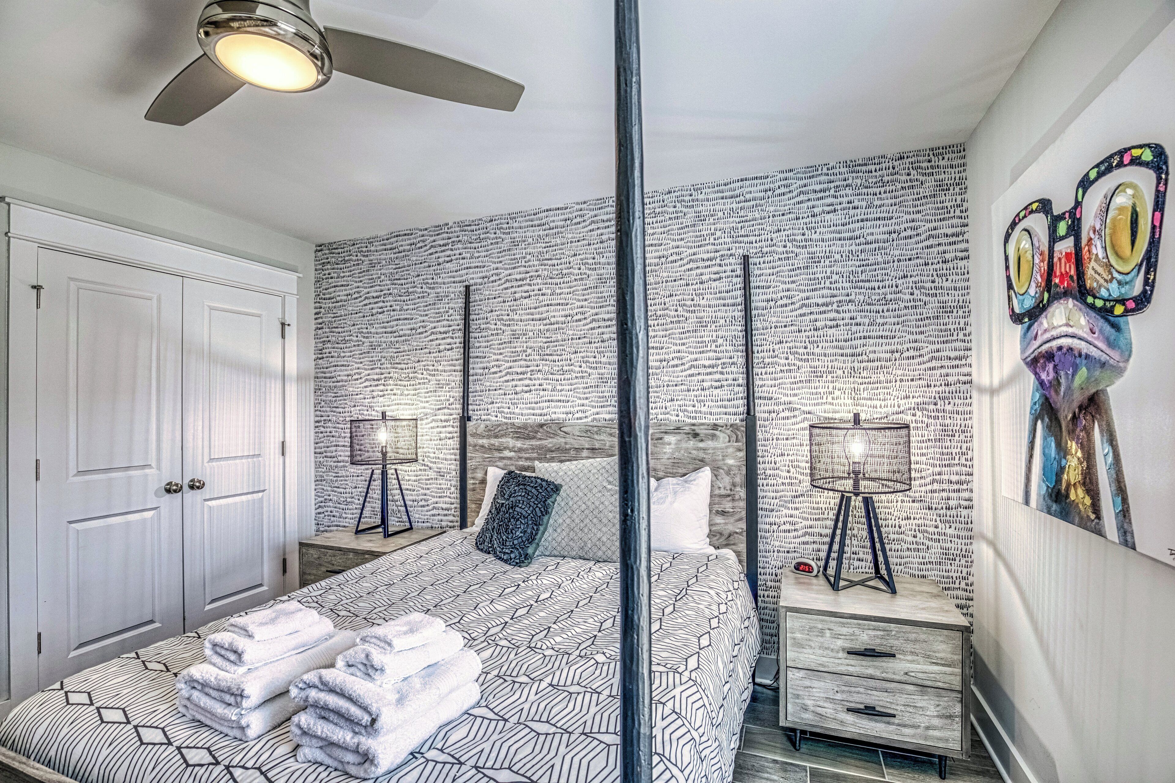 A bedroom with a bed, bedside tables, a ceiling fan, and a wall with a textured pattern.
