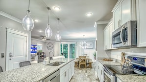 A modern kitchen with granite countertops, stainless steel appliances, and pendant lighting. - (119) Heated Pool, Hot Tub, Walk to the Beach, Elevator, EV Charger (Hilton Head Island)