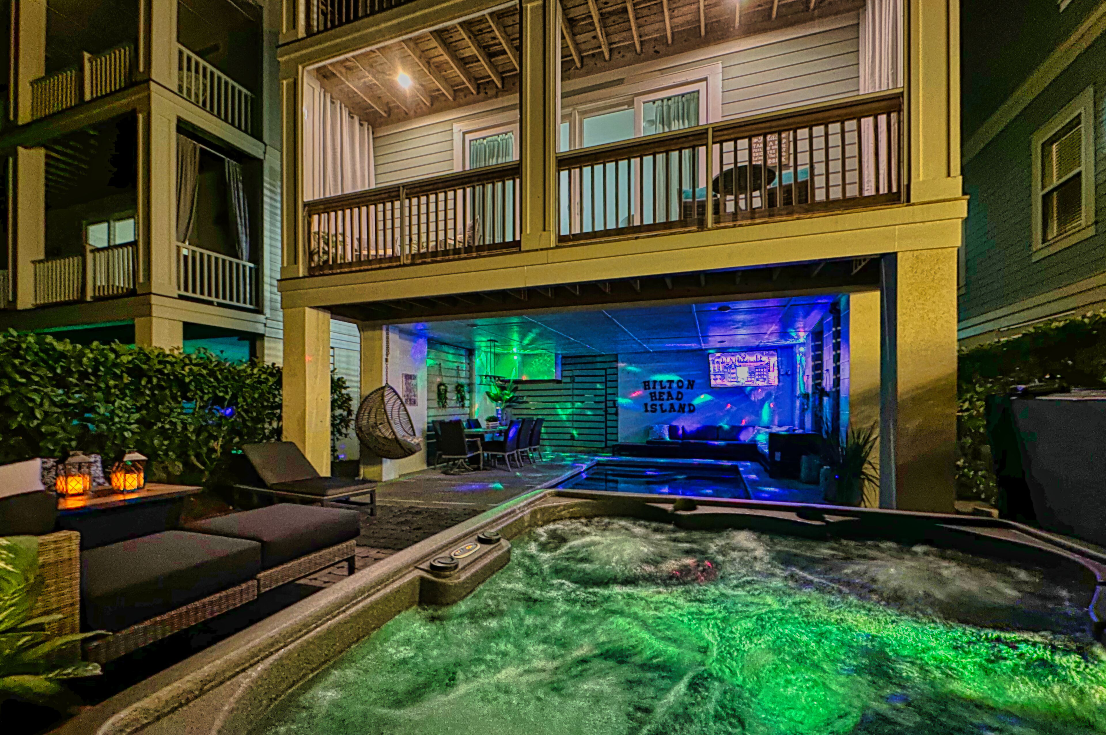 Un área de hidromasaje con sillones reclinables y una piscina, rodeada por un edificio con balcones y un letrero que dice "Hilton Head Island".