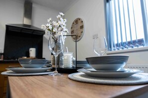 A kitchen counter with a vase of white flowers, two wine glasses, and a clock on the wall. - Casa Lobo's Beautiful Suites +free offroad parking (Wolverhampton)