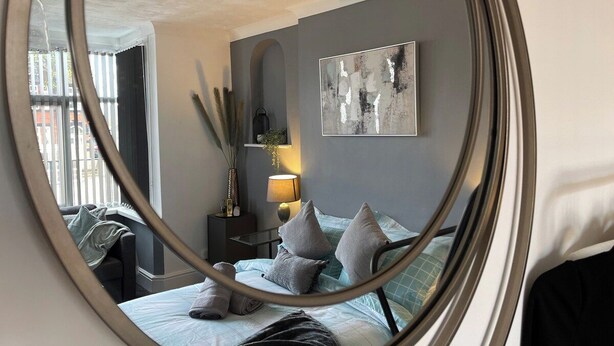 A bedroom with a bed, pillows, a nightstand, a lamp, and a painting on the wall. - Casa Lobo's Beautiful Suites +free offroad parking (Wolverhampton)
