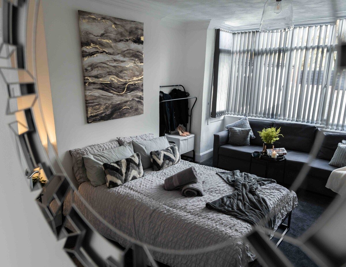Een moderne slaapkamer met een bed, een zithoek en een groot raam.