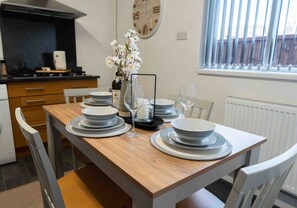 A dining table set with plates, glasses, and a vase of flowers.