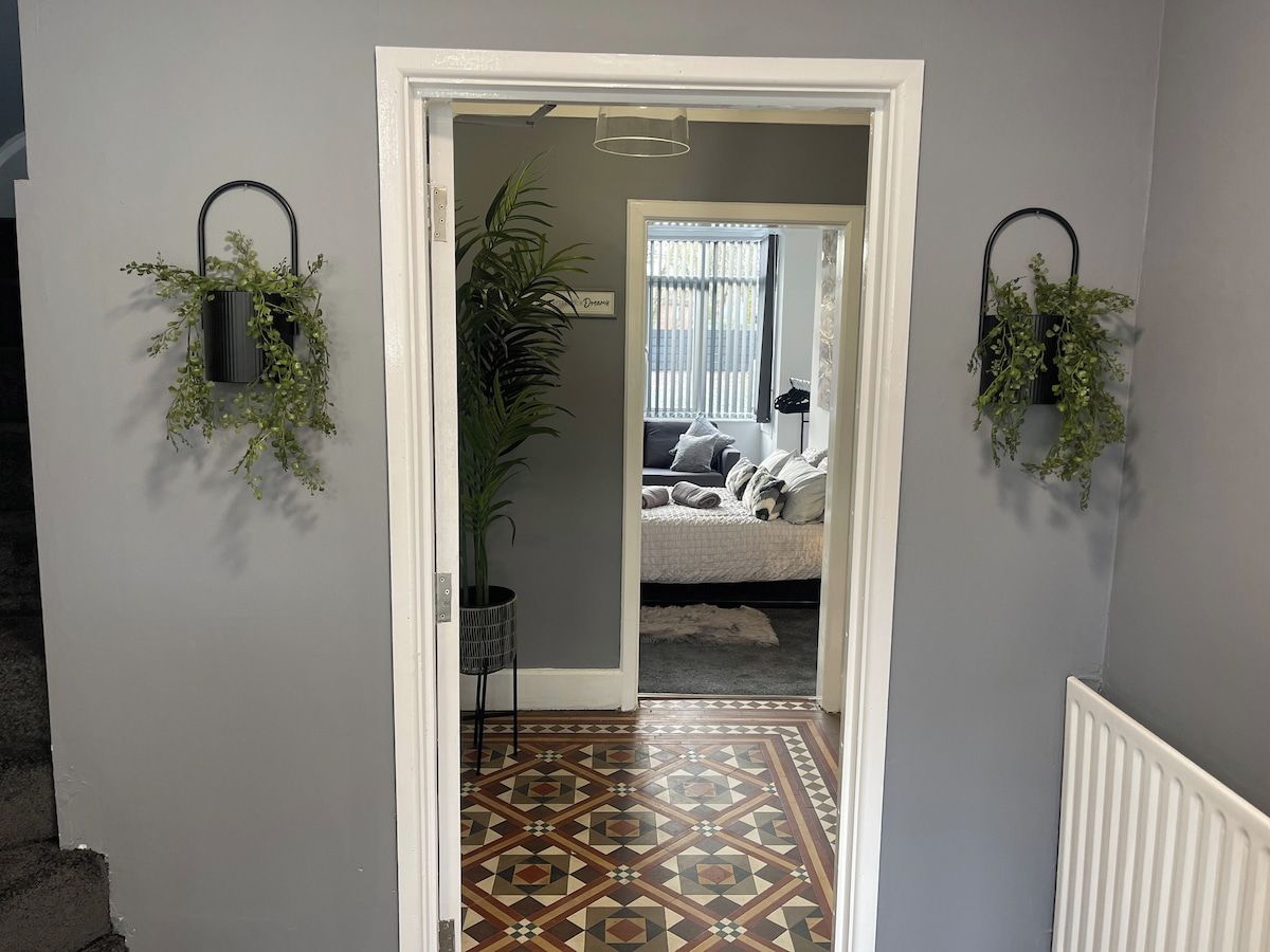 Um corredor com piso estampado leva a um quarto com cama e janela.
