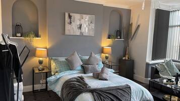 Un dormitorio moderno con una cama, mesitas de noche, una lámpara colgante y un ventanal.
