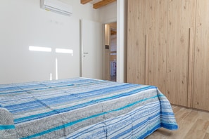 A bedroom with a bed, a wardrobe, and a door leading to another room.