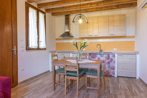 A compact kitchen with wooden cabinets, a built-in oven, and a hanging light fixture. - Maurino Accommodation: Five Minutes from the Beach (Toscana)