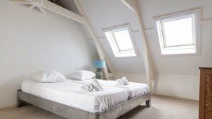 Una camera da letto con un letto, due lucernari, una lampada e un armadio in legno.